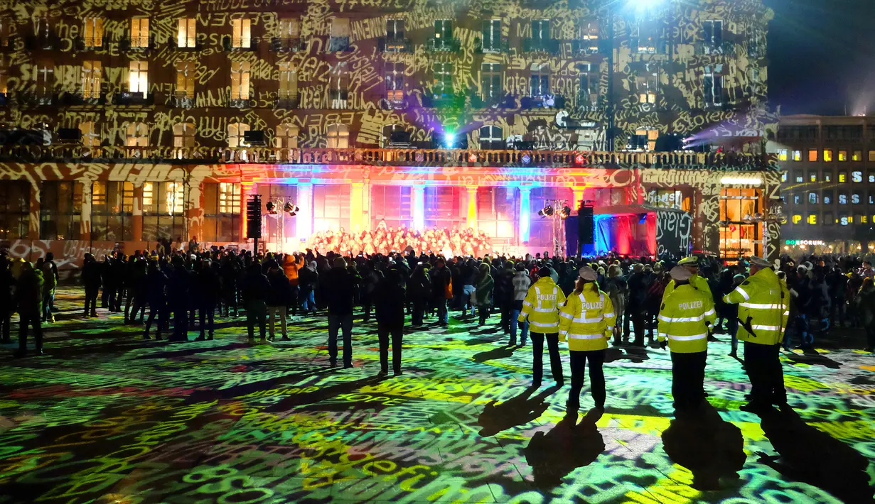 Sejumlah petugas keamanan berjaga di depan gedung Katedral Cologne yang dihiasi instalasi cahaya, Jerman (31/12). Masyarakat dari seluruh dunia sangat antusias menyambut kedatangan tahun baru 2017, termasuk juga masyarakat Jerman. (AFP/Patrik Stollarz)