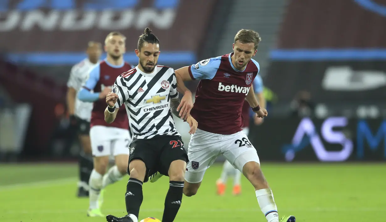 Bek Manchester United, Alex Telles mengumpan bola dari kawalan gelandang West Ham, Tomas Soucek pada pertandingan lanjutan Liga Inggris di stadion London di London, Inggris, Minggu (6/12/2020). MU menang 3-1 atas West Ham. (Adam Davy / Pool via AP)