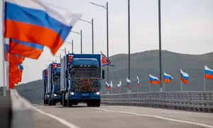 Truk-truk Korea Utara melintasi jembatan baru Rusia-Korea Utara di atas Sungai Tumen saat upacara peresmian pada Senin (7/9/2026), dengan bendera Rusia berkibar di sekitar lokasi. (Dok. Kementerian Transportasi Rusia/AFP)