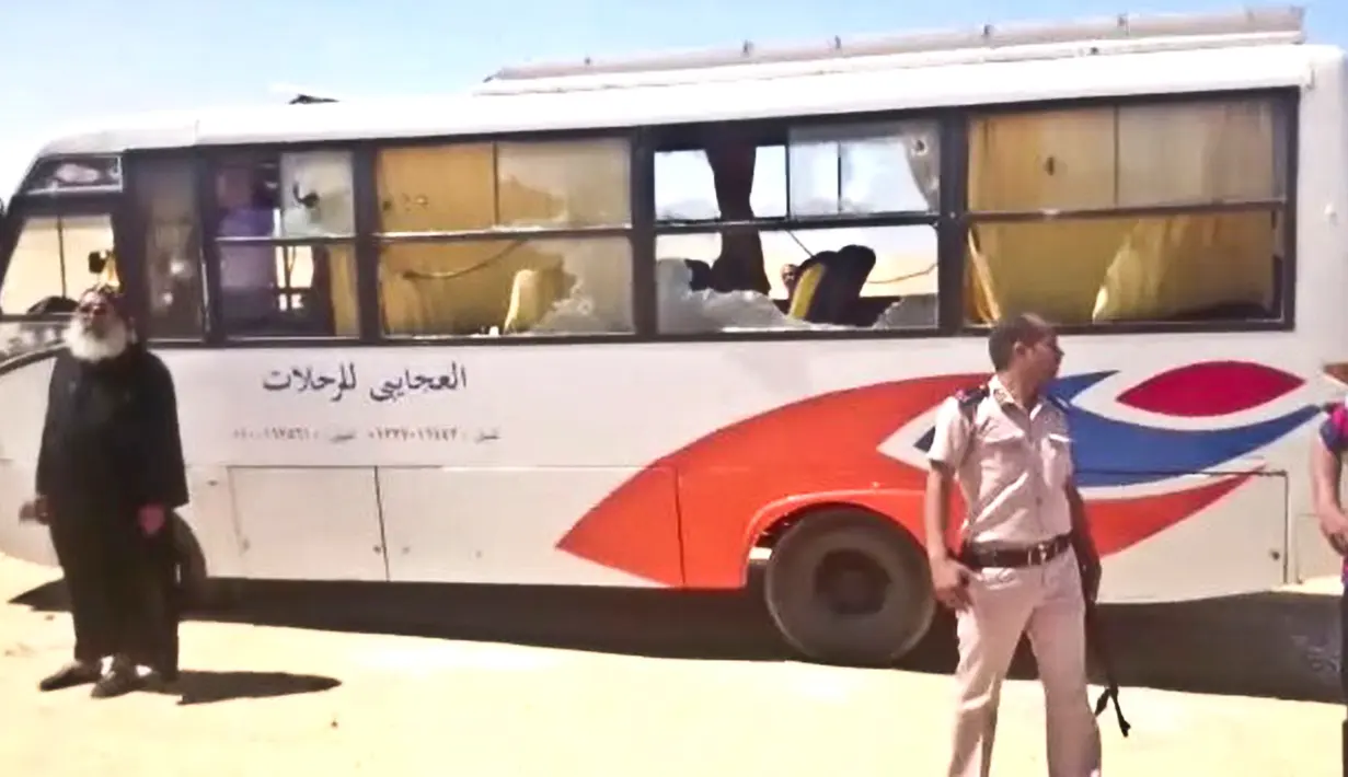 Petugas polisi dan seorang pastur berada di dekat bus yang diserang oleh sekelompok orang bertopeng di Minya, Mesir, (26/5). Jamaah Kristen Koptik merupakan minoritas di Mesir. (Minya Governorate Media office via AP)