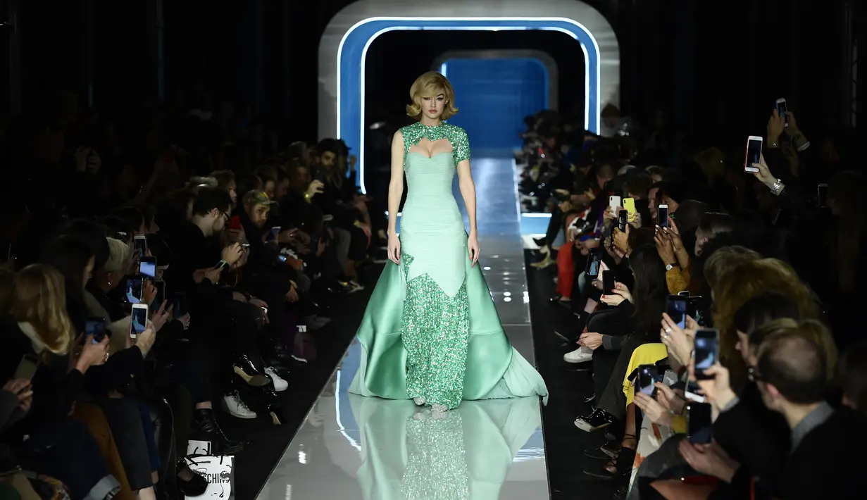 Model AS, Gigi Hadid berjalan membawakan koleksi terbaru Moschino di panggung runway Milan Fashion Week 2018, Rabu (21/2). Gigi terlihat cantik dengan gaun warna hijau muda beraksen sparkling di bagian lengan dan leher serta kakinya. (Miguel MEDINA/AFP)