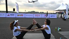 Sekitar 500 peserta yoga dan influencer yang siap dengan kamera mulai berdatangan pada pukul 5:00 pagi, berjalan dalam kegelapan menuju matras mereka di landasan pacu. (MANAN VATSYAYANA / AFP)