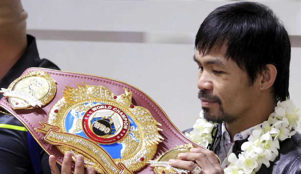 Petinju asal Filipina, Manny Pacquiao melihat sabuk WBO  usai mengalahkan Timothy Bradley setibanya di Bandara Internasional Ninoy Aquino, Manila (14/4). (REUTERS/Romeo Ranoco)