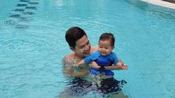 Ardina dan suami sedang menikmati menjadi orang tua. Tak hanya bermain bersama ular, Arie juga ajak si bungsu untuk berenang. (Instagram.com/ardinarasti6)