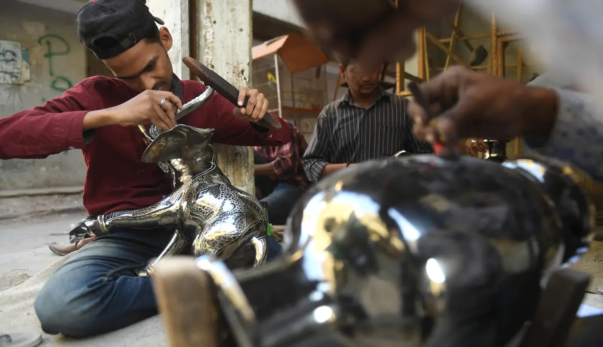 Perajin membuat kerajinan gajah dari kuningan di sebuah bengkel di Karachi, Pakistan (19/11/2019). Perajin kuningan di Karachi biasa membuat patung, hewan, vas lilin dan lentera dari segala bentuk dan ukuran. (AFP Photo/Asif Hassan)