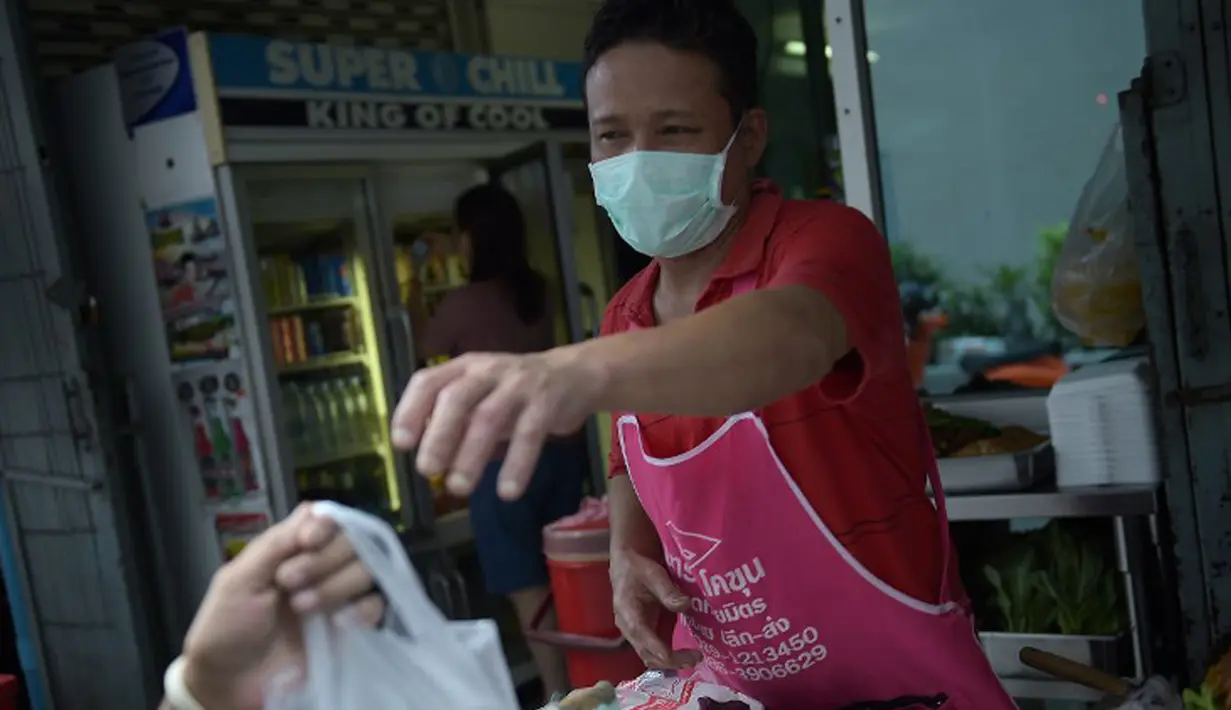 Seorang pria memakai masker memberikan makanan ke pelanggannya di Bangkok, Thailand, (19/6/ 2015). Pemerintah Thailand mengumumkan bahwa seorang pria 75 tahun asal Oman positif terjangkit virus MERS.  (AFP PHOTO/Christophe Archambault)