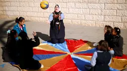 Hiba Al-Sharfa bermain bola bersama muridnya di sekolah Asosiasi Hak Hidup di Kota Gaza (21/12). Hiba Al-Sharfa telah membuktikan bahwa Down Syndrome tidaklah menjadi hambatan untuk meraih cita-citanya. (Reuters/Suhaib Salem)