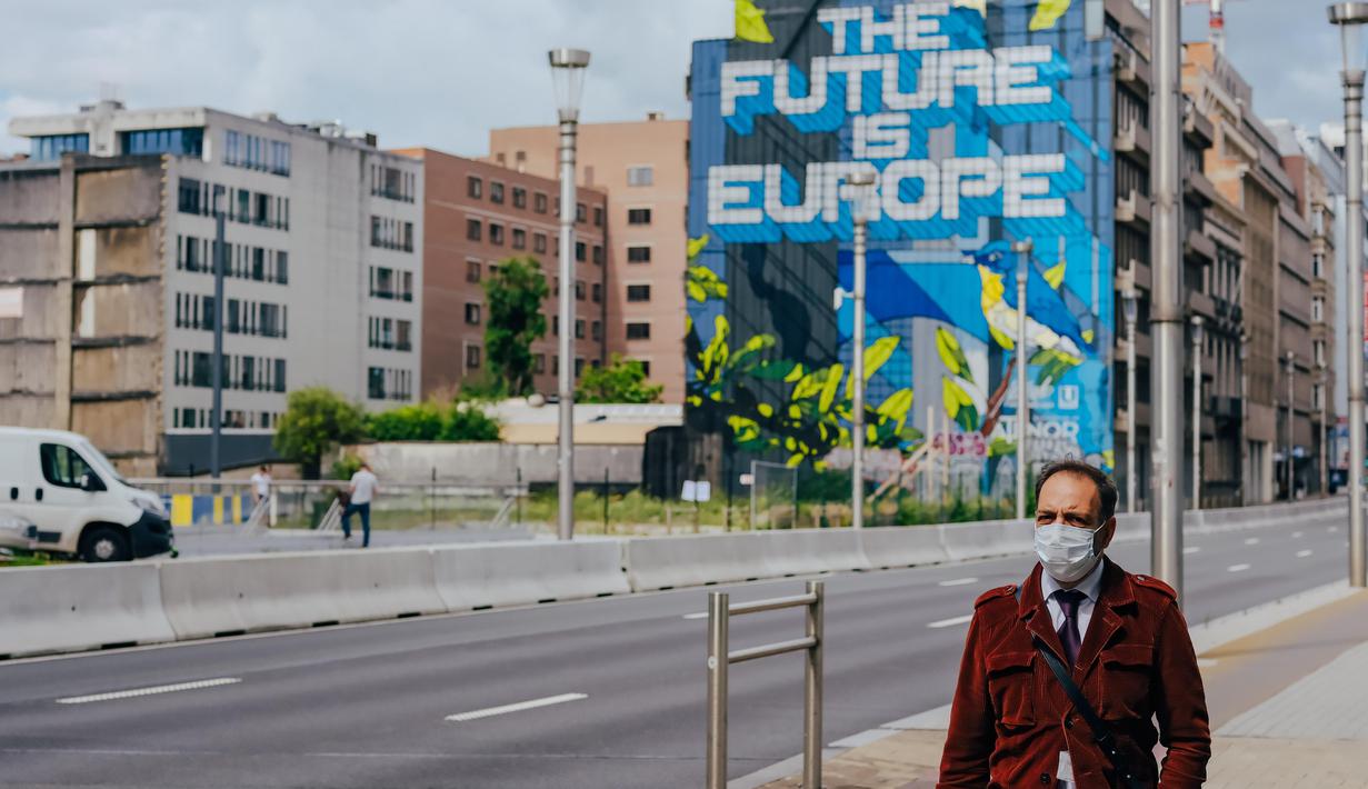 Seorang pria yang mengenakan masker melewati sebuah jalan di Brussel, Belgia, Selasa (7/7/2020). Komisi Eropa memprediksi Ekonomi Eropa akan menghadapi resesi lebih dalam akibat langkah-langkah pengendalian COVID-19 yang berkepanjangan. (Xinhua/Zhang Cheng)