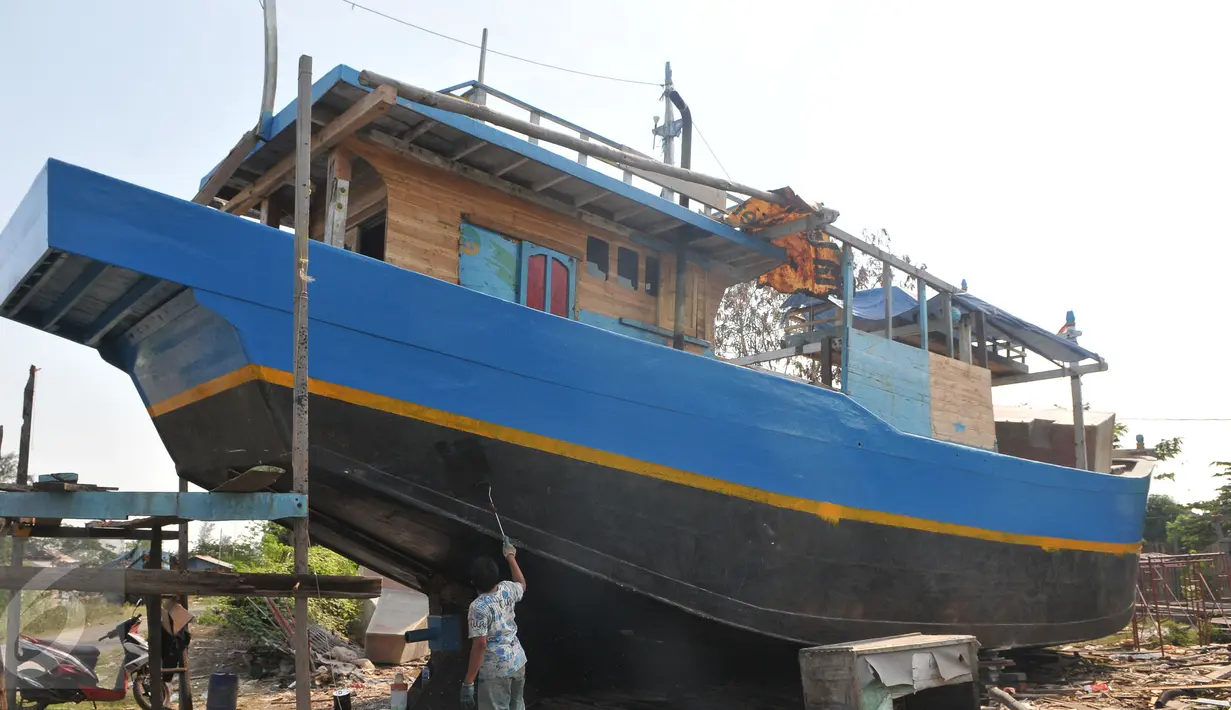 Pekerja mengecat badan kapal saat proses pembuatan di Karangsong, Indramayu, Jabar, Rabu (17/6). Pembuatan kapal berkapasitas sekitar 30 grosstone tersebut dapat memakan waktu 3-6 bulan. (Liputan6.com/Herman Zakharia)