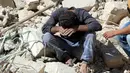 Seorang warga tertunduk usai serangan udara di distrik al-Fardous, Aleppo, Suriah, Rabu (12/10). Serangan udara terhadap kota yang dikuasai oleh pemberontak di Aleppo menewaskan sedikitnya 15 orang. (REUTERS/Abdalrhman Ismail)