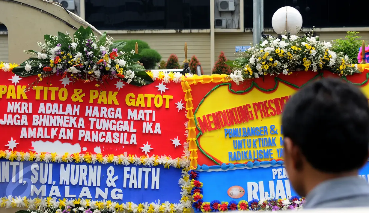Warga melihat deretan karangan bunga yang diletakkan di depan Gedung Baharkam Polri, Jakarta, Rabu (3/5). Ratusan karangan bunga itu terus berdatangan dan mengelilingi gedung Mabes Polri di Jalan Trunojoyo Jakarta. (Liputan6.com/Helmi Fithriansyah)