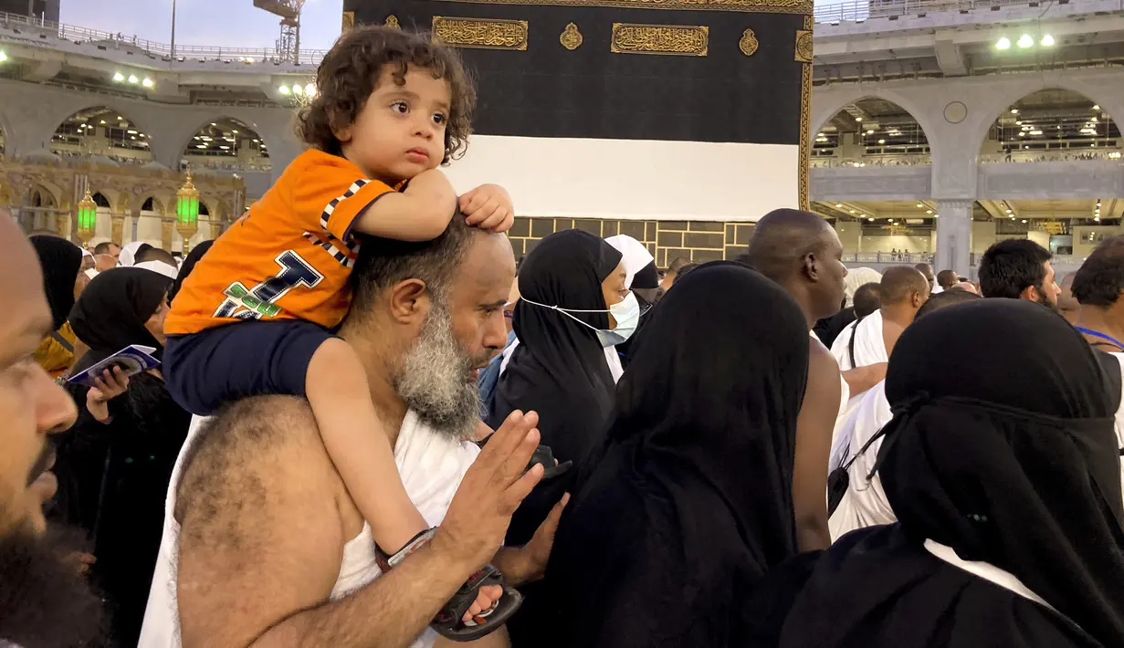 Seorang peziarah muslim menggendong putranya saat dia mengelilingi Ka'bah di Masjidil Haram, Kota Suci Mekkah, Arab Saudi, 5 Juli 2022. Arab Saudi diperkirakan akan menerima satu juta umat muslim untuk melaksanakan ibadah haji yang akan dimulai pada 7 Juli setelah dua tahun dibatasi karena pandemi virus corona COVID-19. (AP Photo/Amr Nabil)
