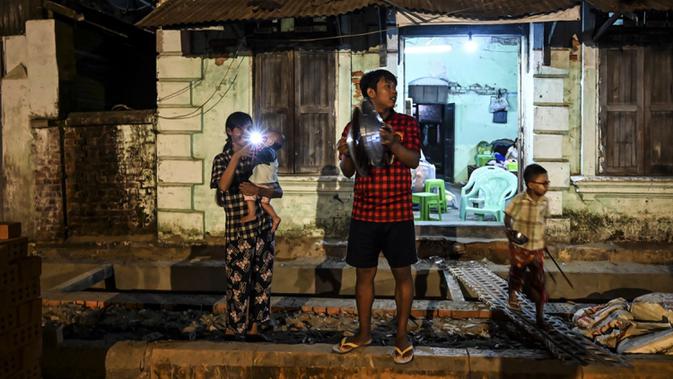 Orang-orang membuat keributan dengan memukul-mukul panci setelah seruan untuk protes keluar di media sosial di Yangon, Myanmar, 3 Februari 2021. Kudeta militer Myanmar terus memicu protes warga dengan membunyikan klakson mobil, menyalakan lampu ponsel, dan memukul-mukul panci. (STR/AFP)