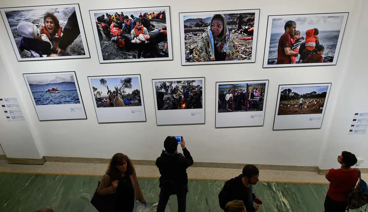 Sejumlah pengunjung mengambil foto saat pameran karya fotografer Agence France-Presse (AFP) mengenai krisis migrasi di Eropa di pusat seni Bozar di Brussels (3/5). Pameran ini berjudul "Puting a Face on the Invisibles. (AFP Photo/John Thys)