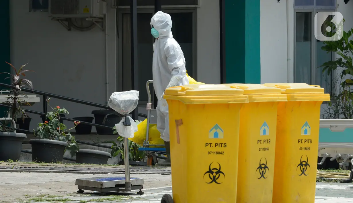 Petugas kesehatan memakai baju APD sedang membersihkan sampah bekas medis di Puskesmas Pamulang, Kecamatan Pamulang, Tangerang Selatan, Banten, Senin (13/04/2020). Sampah bekas medis tes Covid-19 tersebut akan dimusnahkan guna untuk mensteril kawasan puskesmas. (merdeka.com/Dwi Narwoko)