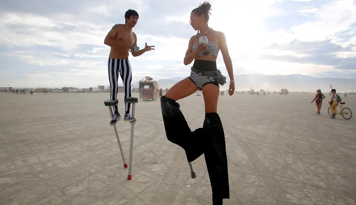 Divine Kumis (kiri) dan Katapult Sandra (kanan), menari menggunakan tiang yang menempel di kaki di Festival Burning Man, di padang pasir Black Rock, Nevada, Amerika Serikat (29/08). (REUTERS/Jim Urquhart)