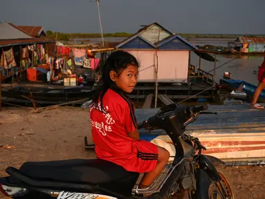 Seorang anak menaiki motor saat bermain di dekat desa terapung di sepanjang sungai Siem Reap, Kamboja (5/12/2019). Sungai Siem Reap adalah sungai yang mengalir melalui Provinsi Siem Reap, di barat laut Kamboja. (AFP/Manan Vatsyayana)