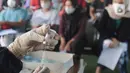 Vaksinator menyiapkan vaksin dosis ketiga untuk warga dan pedagang pasar di kolong flyover Ciputat, Tangerang Selatan, Sabtu (2/4/2022). Vaksinasi booster tersebut diselenggarakan oleh Polsek Ciputat Timur dan Polres Tangerang Selatan. (merdeka.com/Arie Basuki)