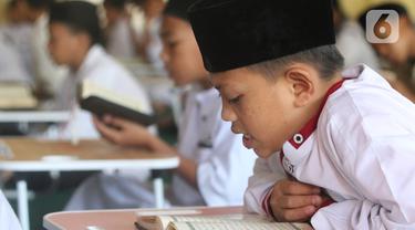 Santri yang masih berusia belasan tahun membaca Al Quran bersama-sama (tadarus) dalam rangka mengkhatamkan Qur'an dengan menerapkan jaga jarak pada Masjid Daarul Qu'ran  Pesantren Al Kautsar, Cibinong, Bogor, Jawa Barat, Minggu (10/04/2022). (merdeka.com/Arie Basuki)