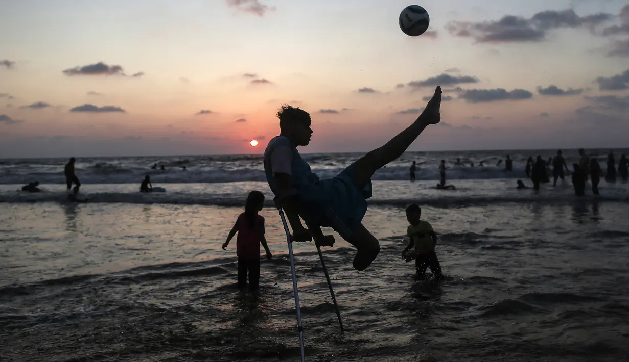 Pemuda Palestina Mohammed Eliwa menendang bola saat bermain di pantai di Kota Gaza (20/9/2019). Eliwa 17 tahun dan Ahmed al-Khoudari 20 tahun kehilangan satu kakinya saat bentrok di perbatasan Israel. (AFP Photo/Mahmud Hams)