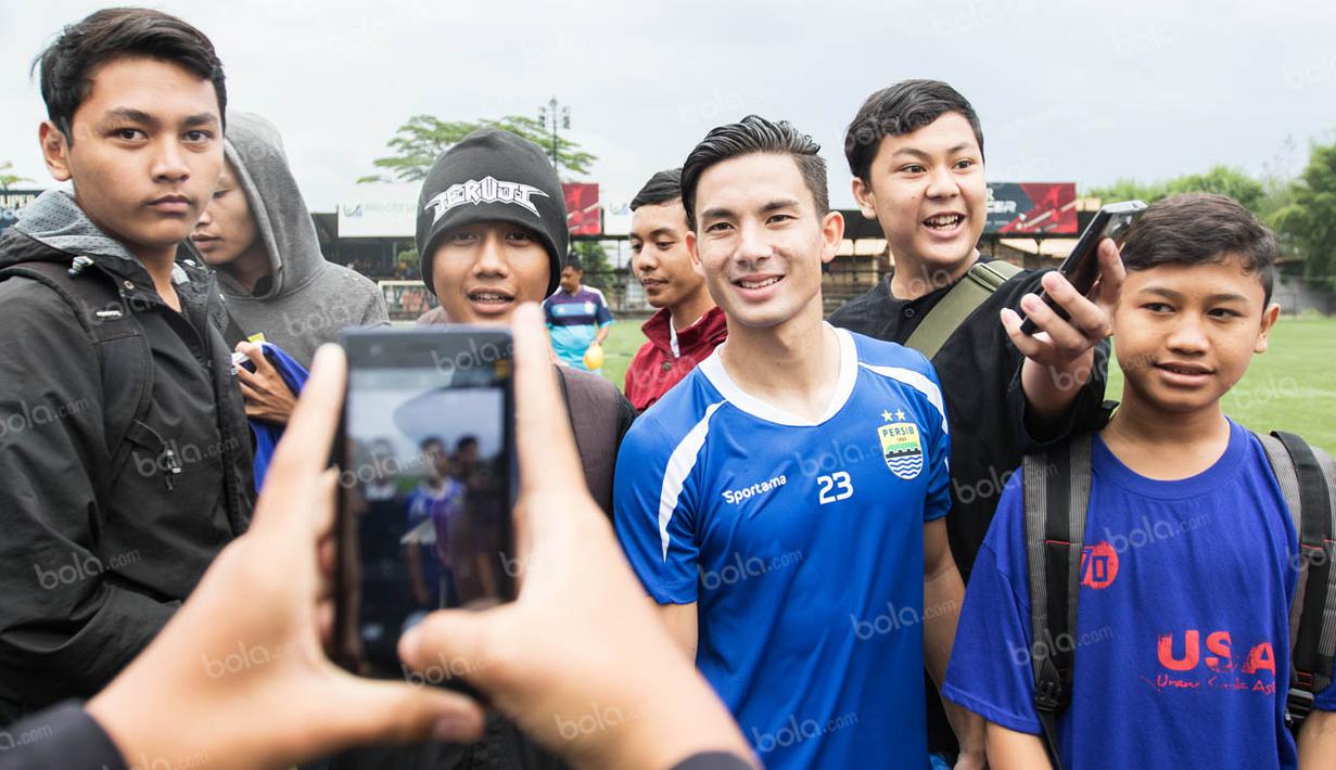 Gelandang Persib, Kim Jeffrey Kurniawan, dengan ramah melayani permintaan para Bobotoh yang memintanya foto bareng usai latihan di Lapangan Progresif, Bandung, Senin (2/5/2016). (Bola.com/Vitalis Yogi Trisna)