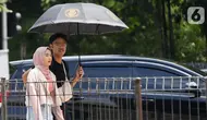 Warga berjalan menggunakan payung di kawasan MH Thamrin, Jakarta, Kamis (21/12/2023). (Liputan6.com/Herman Zakharia)