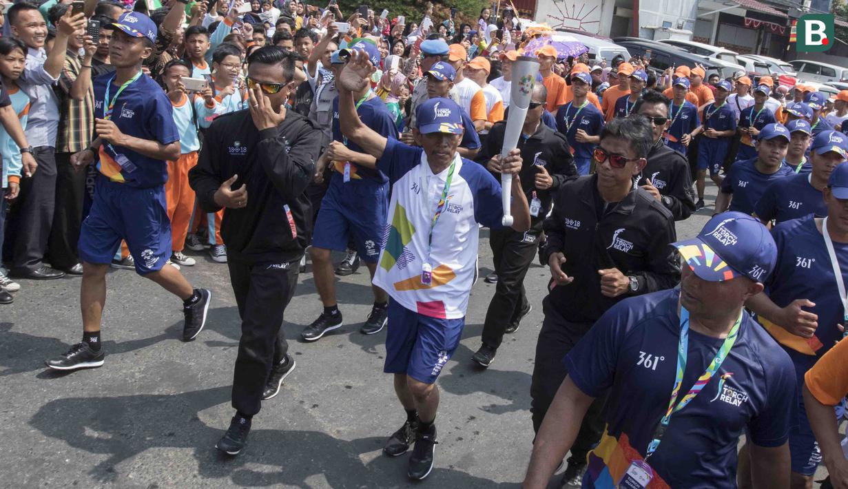 Pebalap sepeda legendaris Indonesia, Sutiyono, berlari saat mengikuti pawai obor Asian Games XVIII di Lampung, Rabu (8/8/2018). Sebanyak 53 kota di Indonesia akan dilalui oleh obor Asian Games. (Bola.com/Reza Bachtiar)