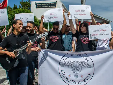 Para demonstran Tunisia membentangkan spanduk selama protes terhadap pemilik restoran dan bar yang menutup tokonya selama puasa bulan suci Ramadan di Tunis, Tunisia, (27/5). (AP Photo / Hassene Dridi)