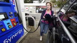 Jennifer Quinn mengisi SUV-nya di sebuah pompa bensin di Needham, Massachusetts, Amerika Serikat, 7 Maret 2022. Harga bensin AS menembus USD 4 per galon atau naik ke level tertinggi sejak Juli 2008 imbas sanksi global atas Rusia karena menyerang Ukraina. (AP Photo/Steven Senne)
