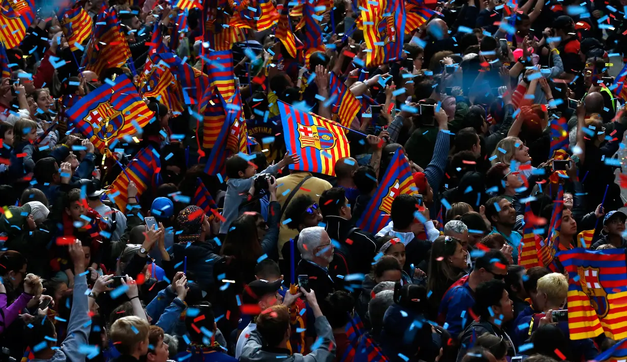 Para warga dan penggemar berkumpul untuk menyambut pemain Barcelona saat melakukan parade di Barcelona (30/4). Parade ini untuk merayakan juara La Liga Spanyol yang berhasil diraih oleh tim sepak bola Barcelona.  (AP/Manu Fernandez)
