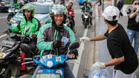 Relawan membagikan masker kepada pengemudi ojek online di Bundaran HI, Jakarta, Selasa (17/3/2020). Sebanyak 3.000 masker dibagikan secara gratis sebagai salah satu bentuk keprihatinan sekaligus berpartisipasi dalam upaya mencegah penyebaran virus corona COVID-19. (Liputan6.com/Faizal Fanani)