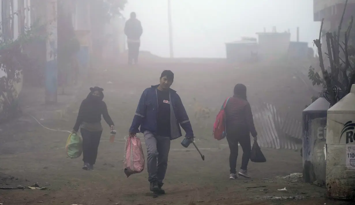 <p>Warga berjalan melalui kabut dingin dan tebal pada hari resmi pertama musim dingin, di lingkungan Ticlio Chico di pinggiran Lima, Peru, Selasa (21/6/2022). Suhu di ibu kota adalah yang terendah dalam 25 tahun, menurut National Layanan Meteorologi dan Hidrologi Peru. (AP Photo/Martin Mejia)</p>