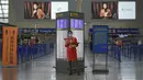 Staf pesawat yang mengenakan masker berdiri di dekat konter check-in yang sepi di Bandara Internasional Pudong, Shanghai, Minggu (25/7/2021). China telah menutup jalur kereta api dan pelabuhan, serta membatalkan jadwal penerbangan sebelum topan In-Fa diperkirakan mendarat. (AP Photo/Andy Wong)