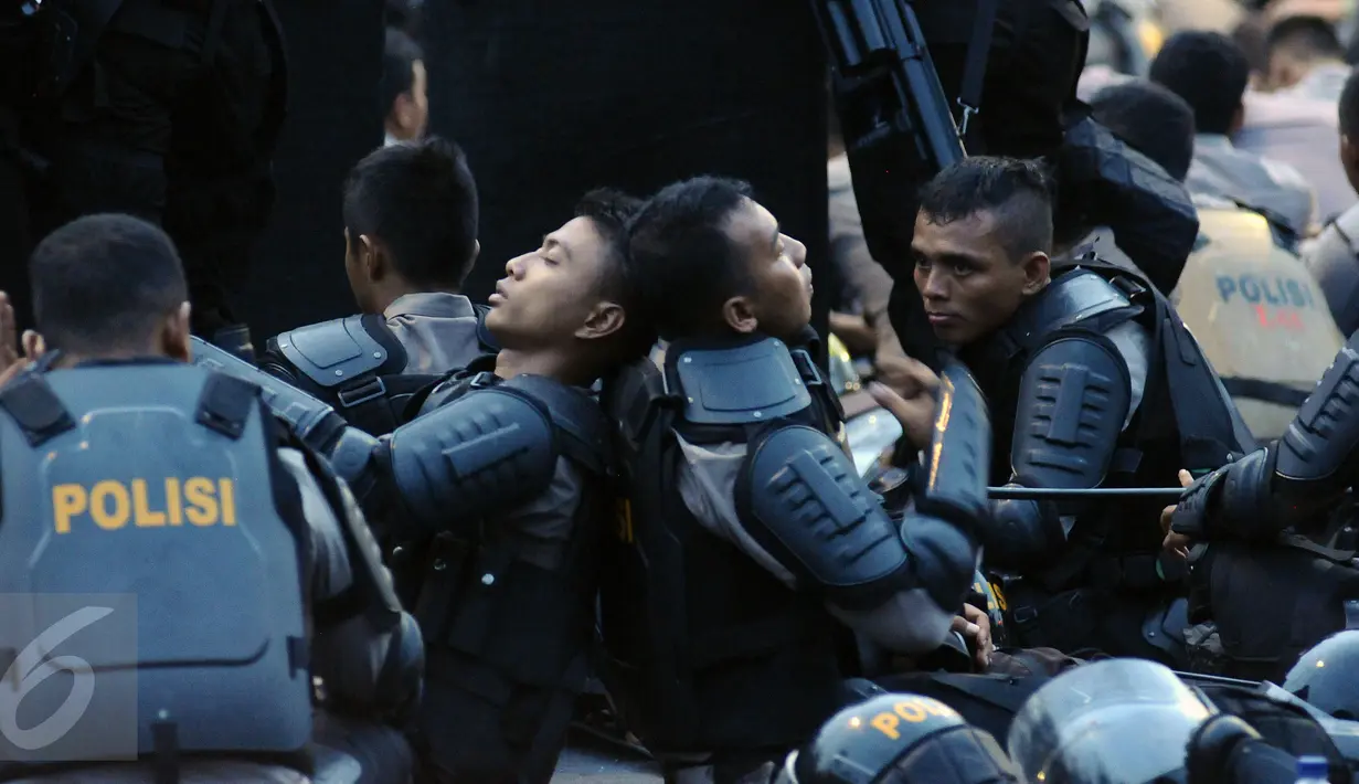 Polisi duduk beristirahat saat berjaga di depan Istana Negara, Jakarta, Jumat (4/11). Ribuan aparat gabungan disiagakan saat massa melakukan aksi menuntut penegakan hukum kasus dugaan penistaan agama. (Liputan6.com/Helmi Fithriansyah)