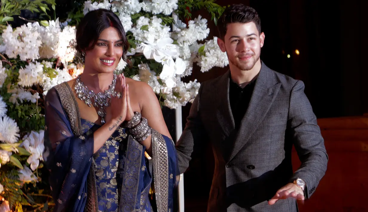 Pasangan aktris Bollywood Priyanka Chopra dan musisi Nick Jonas menyapa fotografer saat resepsi pernikahan mereka di Mumbai, Rabu (19/12). Resepsi kedua Priyanka Chopra dan Nick Jonas digelar dua minggu setelah resepsi yang pertama. (AP/Rajanish Kakade)