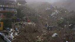 Petugas penyelamat dan penduduk mencari korban di daerah yang rusak akibat tanah longsor di Petropolis, Brasil, Rabu (16/2/2022). Hujan yang sangat deras memicu tanah longsor dan banjir di wilayah pegunungan di negara bagian Rio de Janeiro. (AP Photo/Silvia Izquierdo)