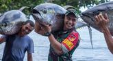 Dengan senyum lebarnya, Aprilio Perkasa Manganang tampil kuat saat membantu nelayan membawa tuna sirip kuning yang berukuran besar. (FOTO: instagram.com/manganang92/)
