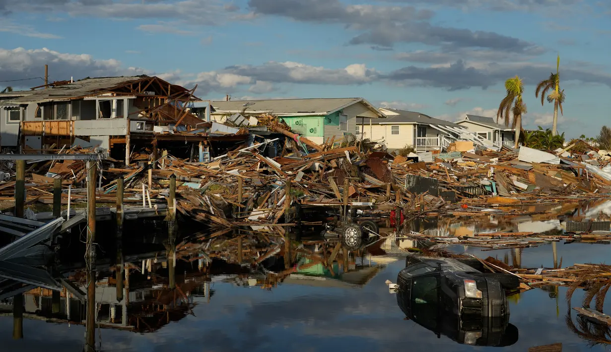 Mobil dan puing-puing dari rumah yang hanyut berjejer di kanal setelah diterjang Badai Ian di Pulau San Carlos, Pantai Fort Myers, Florida, Rabu (5/10/2022). Menurut New York Times terdapat 400 bangunan dibagian utara pulau yang hancur atau rusak parah. (AP Photo/Rebecca Blackwell)