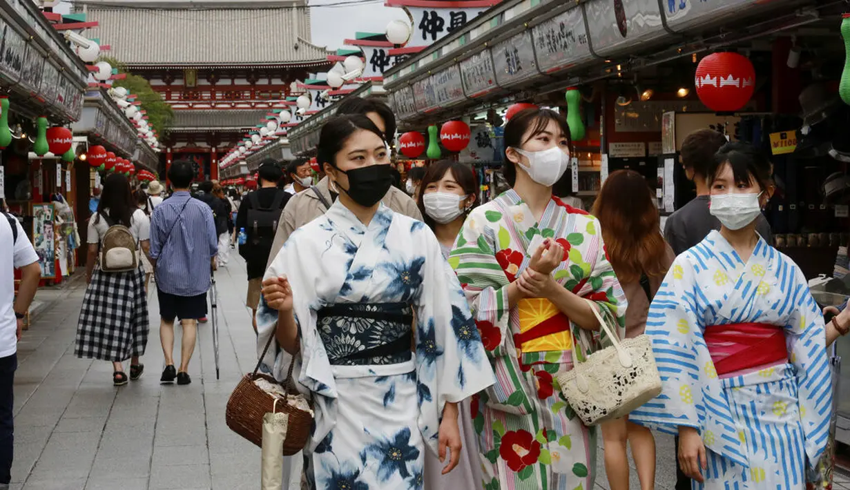 Wanita mengenakan yukata dan masker untuk melindungi diri dari penyebaran virus corona berjalan di jalan perbelanjaan Asakusa Nakamise di Tokyo, Jumat (13/8/2021). Yukata dipakai agar badan menjadi sejuk di sore hari atau sesudah mandi malam berendam dengan air panas. (AP Photo/Koji Sasahara)