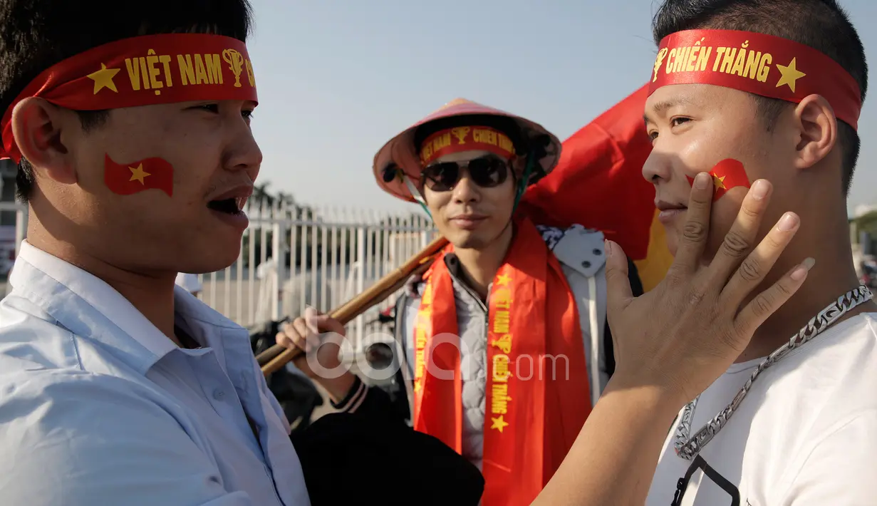 Suporter Vietnam saling membantu menempel logo bendera negaranya pada wajah masing-masing sebelum laga semifinal Piala AFF 2016 di Stadion Nasional My Dinh, (07/12/2016). (Bola.com/Peksi Cahyo)