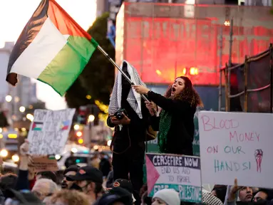 Seorang pengunjuk rasa mengibarkan bendera Palestina saat melakukan protes menentang perang Israel-Hamas bersamaan dengan KTT APEC yang berlangsung di San Francisco, Amerika Serikat, Selasa (14/11/2023). (AP Photo/Godofredo A. Vásquez)