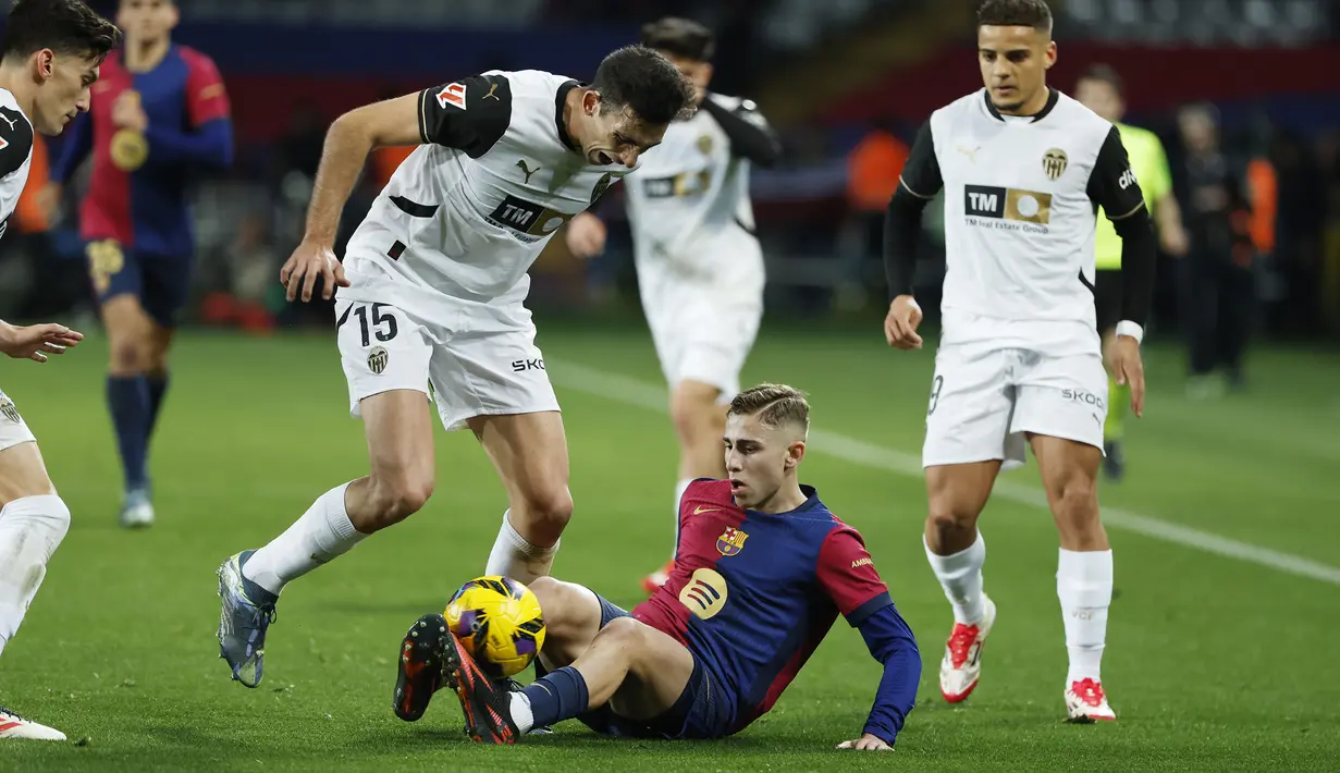 Pemain Barcelona, Fermin Lopez berebut bola dengan pemain Valencia, Cesar Tarrega pada laga lanjutan Liga Spanyol 2024/2025 di Estadi Olimpic Lluis Companys, Barcelona, Spanyol, Senin (27/01/2025) dini hari WIB. (AP Photo/Joan Monfort)
