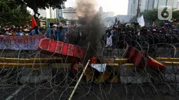 Sejumlah elemen mahasiswa menggelar demo dengan membakar pembatas jalan di kawasan Patung Kuda, Jakarta Pusat, Selasa (13/9/2022). Demo tersebut untuk menolak kebijakan pemerintah menaikkan harga bahan bakar minyak (BBM). (Liputan6.com/Johan Tallo)