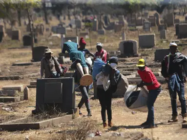 Pedagang Zimbabwe membawa dagangannya di kuburan setelah kabur dari kejaran polisi yang mengejar mereka setelah kedapatan berjualan dari tempat yang tidak ditentukan karena pembatasan COVID-19 di Harare, Kamis (29/7/2021). (AP Photo/Tsvangirayi Mukwazhi)