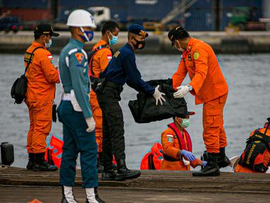 Petugas membawa body part dari kapal Basarnas di JICT II Tanjung Priok, Jakarta, Jumat (15/1/2021).  Badan SAR Nasional (Basarnas) kembali menerima paket kiriman hasil pencarian hari ketujuh. (Liputan.com/Faizal Fanani)