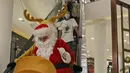 Petugas yang mengenakan kostum Sinterklas menaiki eskalator saat berkeliling menghibur pengunjung di Senayan City Mall, Jakarta, Jumat (25/12/2020). Pengunjung bisa berswafoto dan menikmati momen Natal bersama keluarga dan orang terkasih dengan "Santa and Friend". (Liputan6.com/Herman Zakharia)