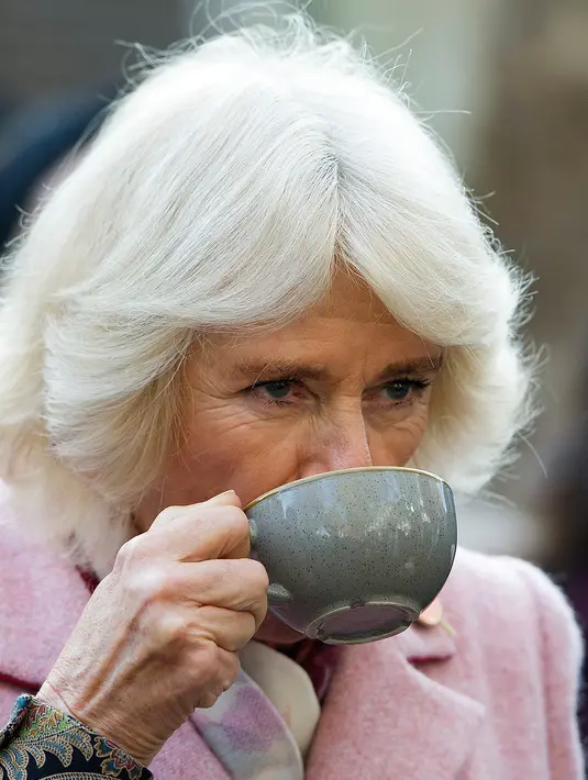Duchess of Cornwall, Camilla Parker Bowles menikmati teh ketika mengunjungi Swiss Cottage Farmers Market di London utara, Rabu (6/11/2019). Kunjungan Pangeran Charles dan Camila untuk mengucapkan selamat dan memperingati ulang tahun ke-20 pasar tersebut. (Eddie Mulholland / POOL / AFP)