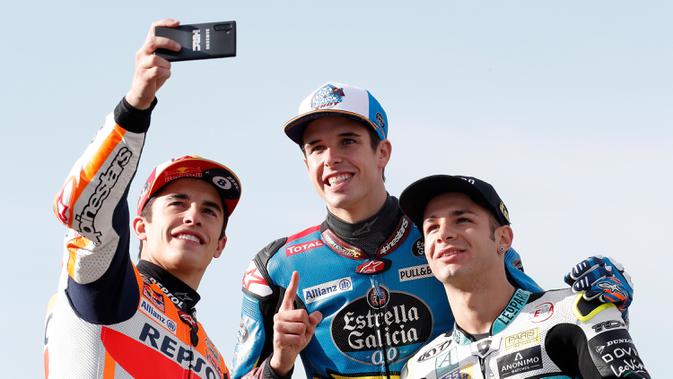 Tiga Juara Dunia di MotoGP: Pembalap MotoGP Marc Marquez (kiri) bersama pembalap Moto2 Alex Marquez (tengah) dan pembalap Moto3 Lorenzo Dalla Porta (kanan) berswafoto di depan Valencia Motorcycle Grand Prix, Spanyol, Minggu (17/11/2019). (AP Photo/Alberto Saiz)