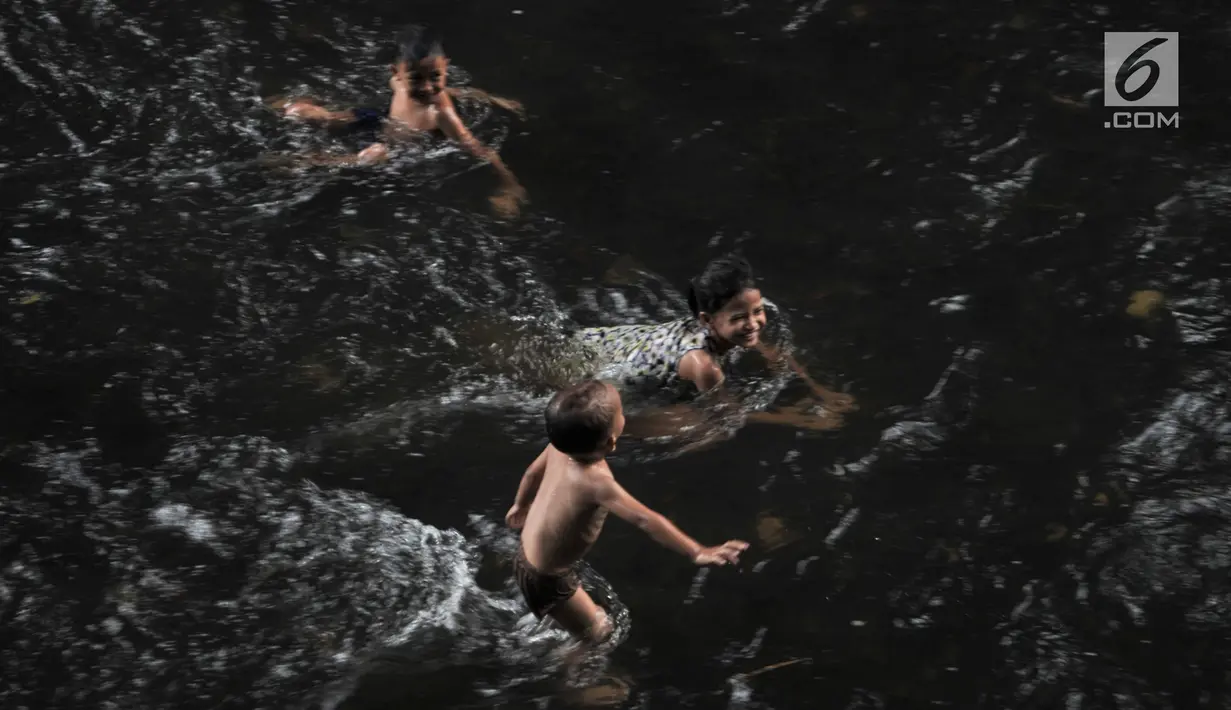 Anak-anak berenang di Sungai Ciliwung, Depok, Jawa Barat, Kamis (4/7/2019). Menurunnya debit air Sungai Ciliwung akibat musim kemarau dimanfaatkan warga setempat sebagai tempat wisata gratis untuk mengajak anak berenang. (merdeka.com/Iqbal Nugroho)