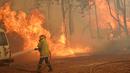 Seorang petugas pemadam kebakaran menangani kobaran api di dekat Wooroloo, timur laut Perth, Australia, Selasa (2/1/2021). Asap dan api dari kebakaran hutan membakar kota terbesar keempat di Australia ini, di tengah pemberlakuan lockdown virus corona COVID-19. (Evan Collis/DFES via AP)